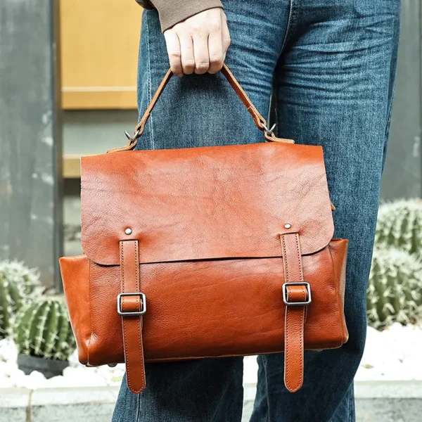 1 (1) Brown leather satchel bag held in hand, product shot