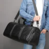 1 (5) Man carrying black leather duffle bag, casual denim style