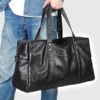 12 Man carrying black leather duffle bag, casual denim style