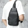 12 Man carrying black leather sling bag, back view