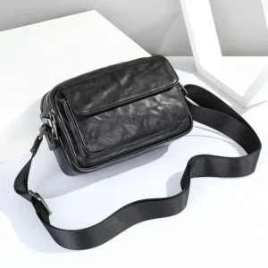 Black leather crossbody bag with wide strap, studio shot