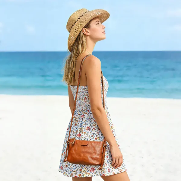 Woman carrying brown leather crossbody bag on beach