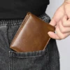 Hand holding a brown leather bifold wallet, casual style
