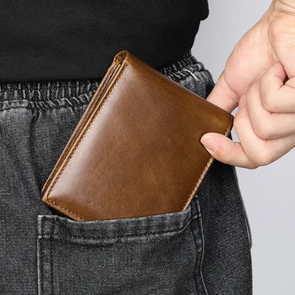 Hand holding a brown leather bifold wallet, casual style