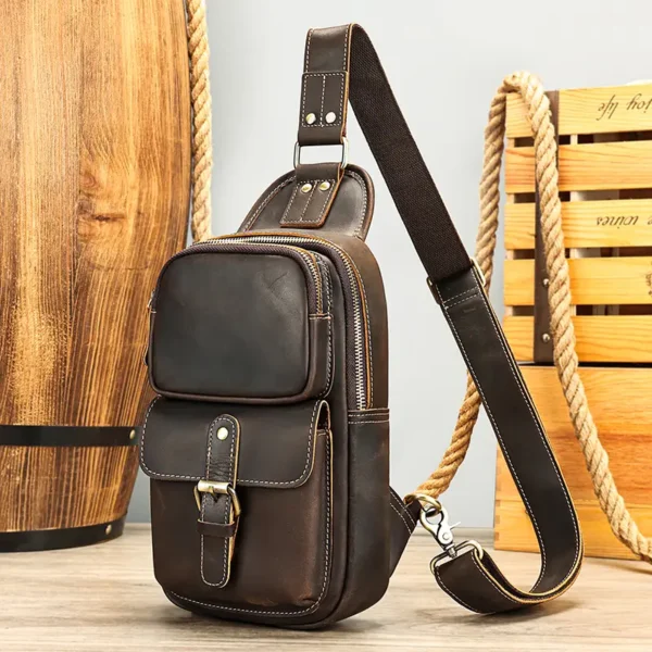Brown leather sling backpack on wooden background, rustic style