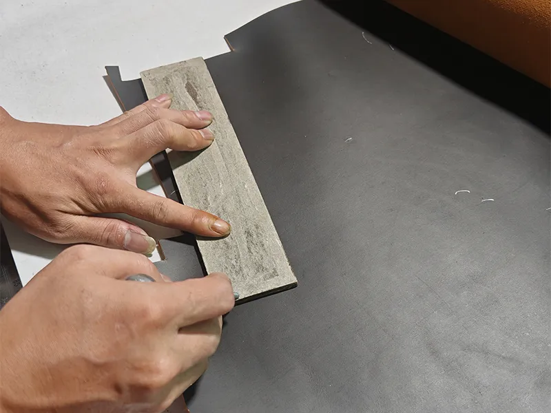 Workers cut and align genuine leather pieces for leather bag production