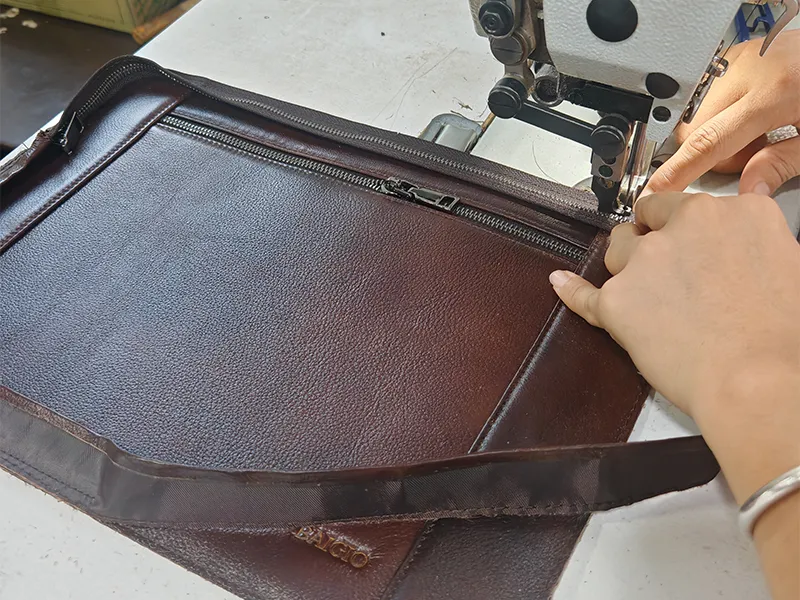 Skilled worker stitching genuine leather bag on industrial sewing machine