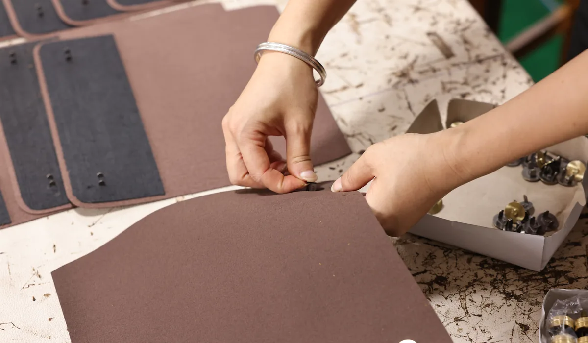 Hands fitting a metal component to a cut leather panel