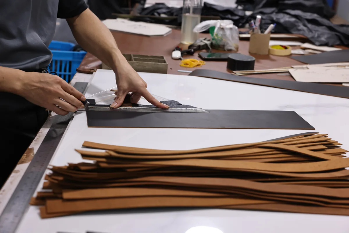 Hands aligning cut leather panels during batch preparation