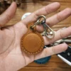 Brown PY-028 leather AirTag holder keychain shown in hand