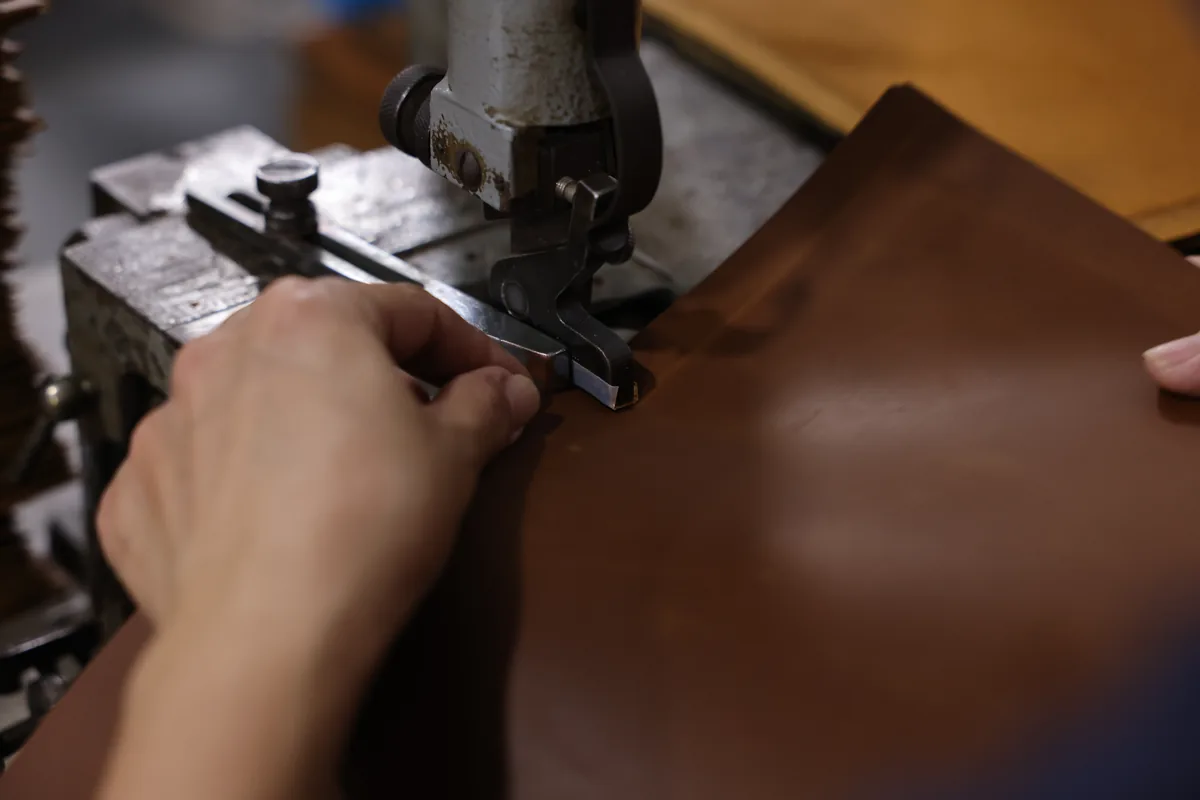 Close view of a machine working along the edge of brown leather