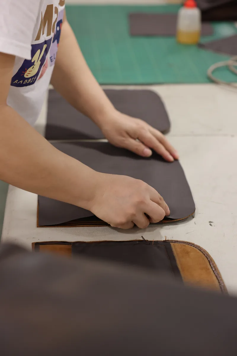 Hands checking the flexibility and surface of a dark leather panel