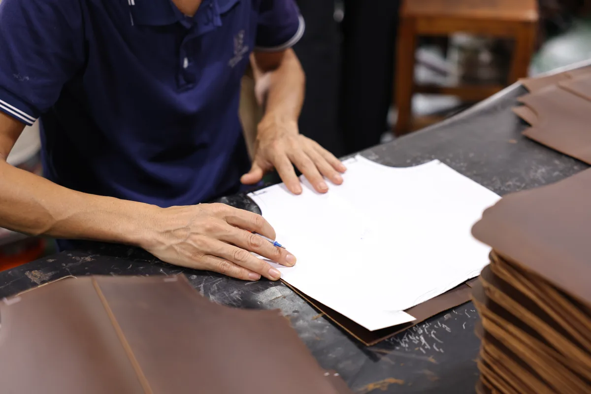 Worker aligning a paper bag pattern on brown leather