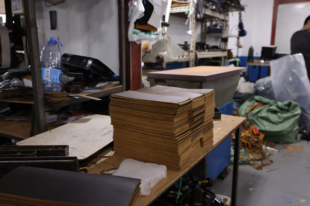 Stacks of leather bag pattern boards beside workshop equipment