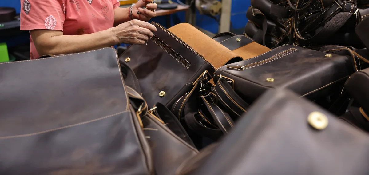 Worker checking a dark leather bag during workshop assembly